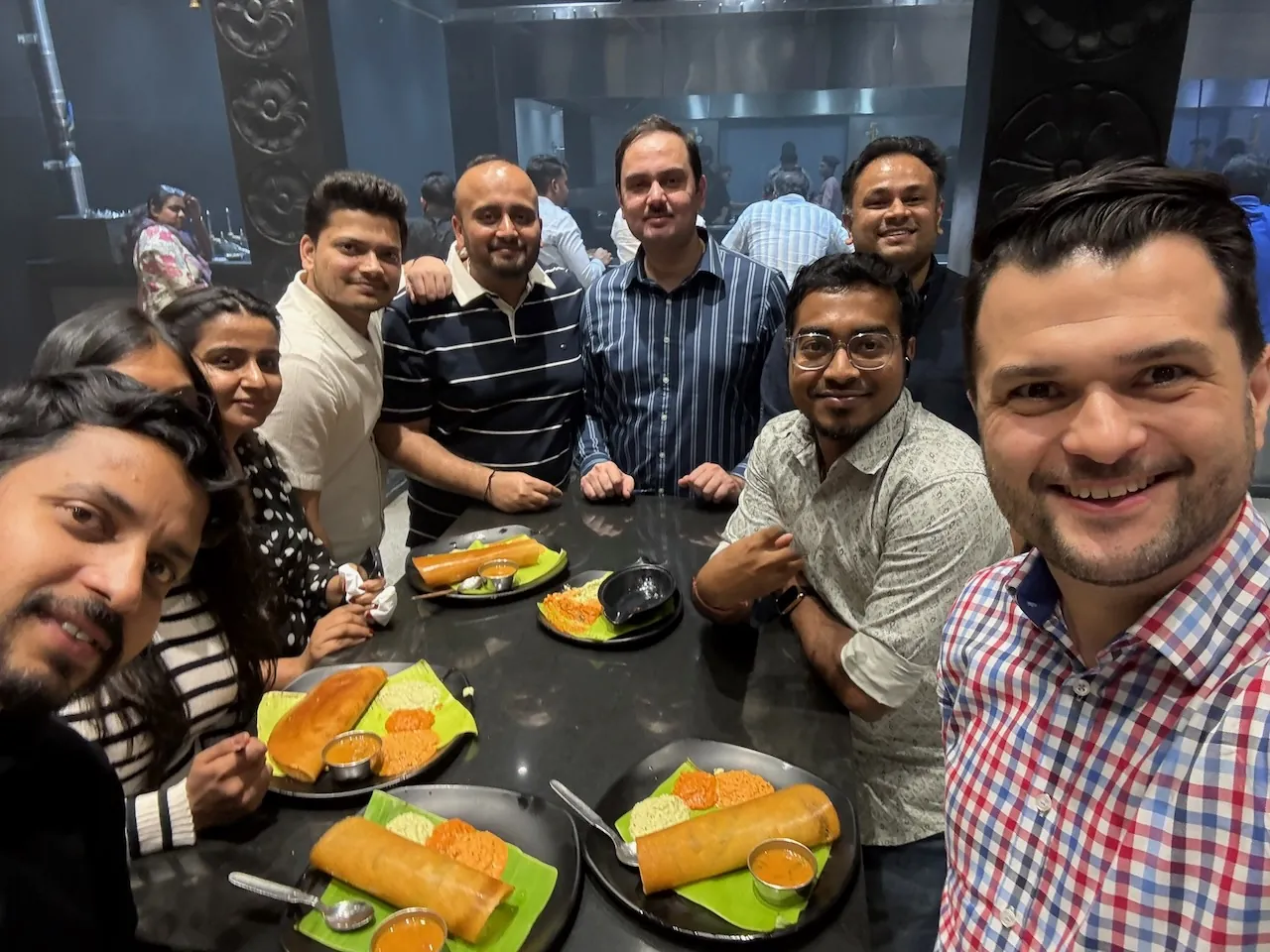 Filipe taking a selfie with his team around a dinner table, sharing dosas